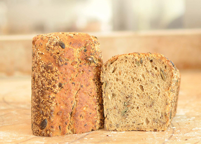Frisch gebackenes Saatenbrot auf bemehltem einem Holzbrett.